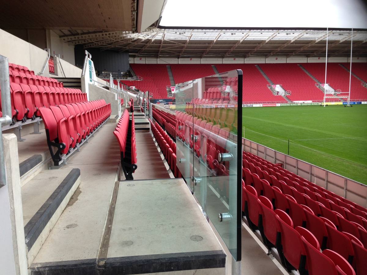 Glass balustrade along stadium seating overlooking the pitch